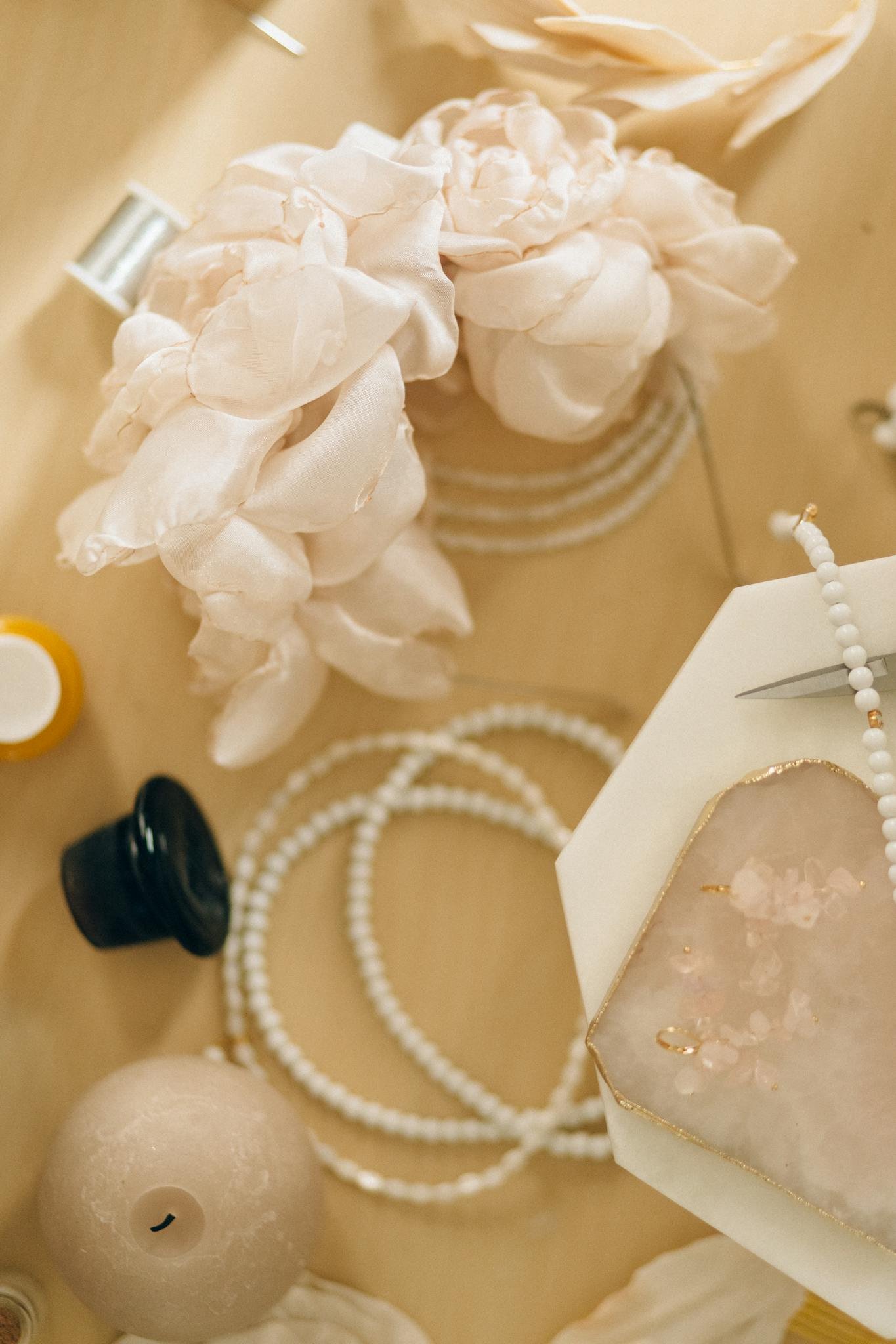 A beautifully arranged flat lay of beaded jewelry and delicate floral accessories on a wooden surface.