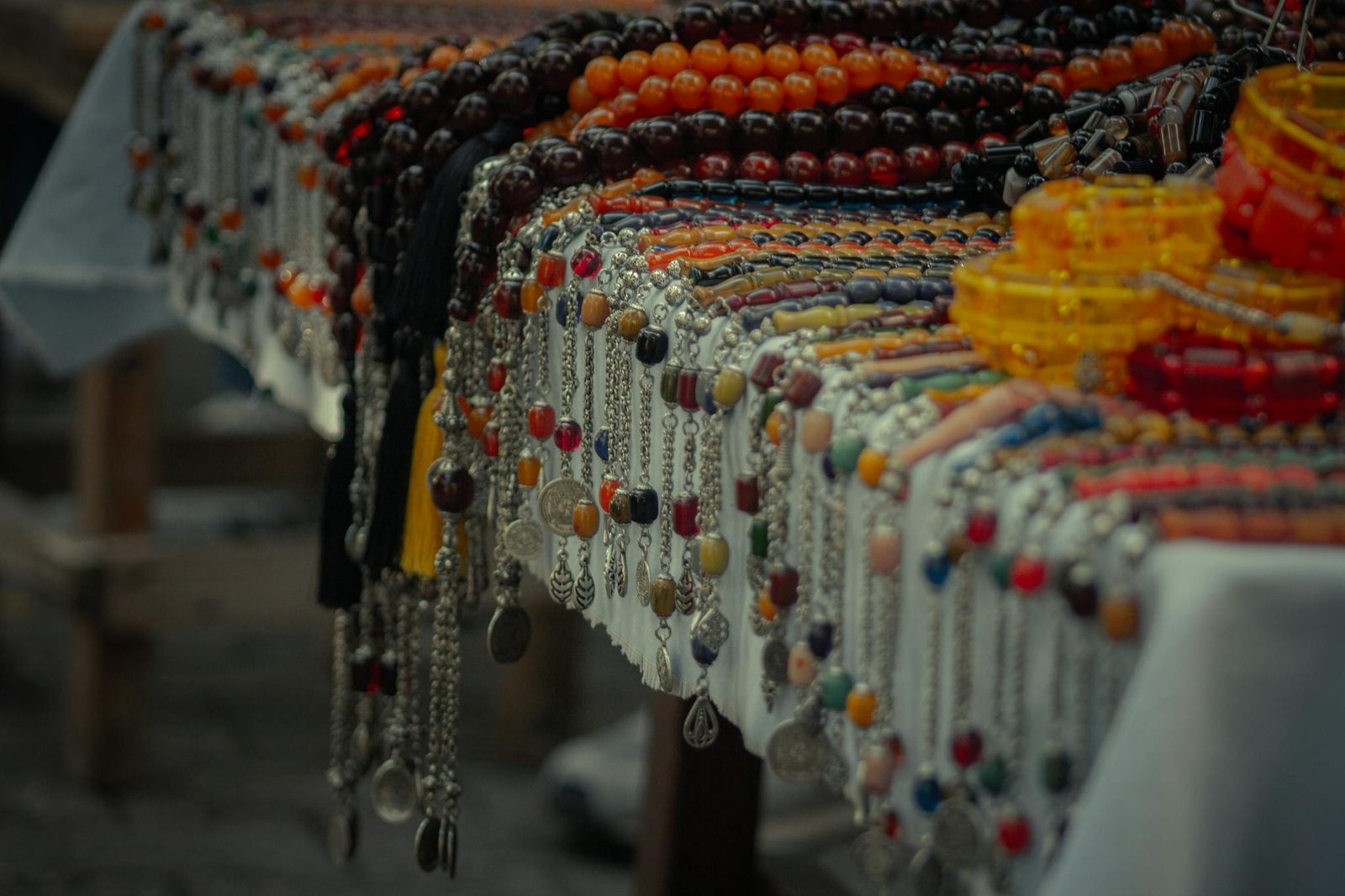 Assortment of colorful bead necklaces and bracelets displayed at an outdoor market stall.