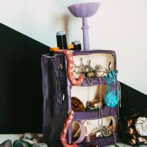 Colorful jewelry stand with assorted accessories and creative ceramic design.