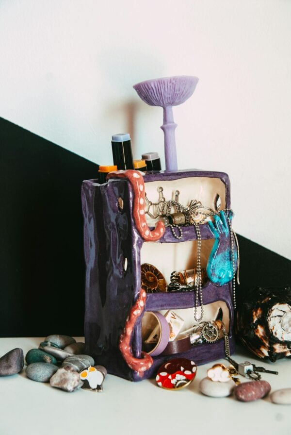 Colorful jewelry stand with assorted accessories and creative ceramic design.