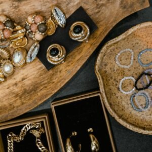 Top view of assorted handmade earrings, rings, and bracelets on ceramic and wooden trays.